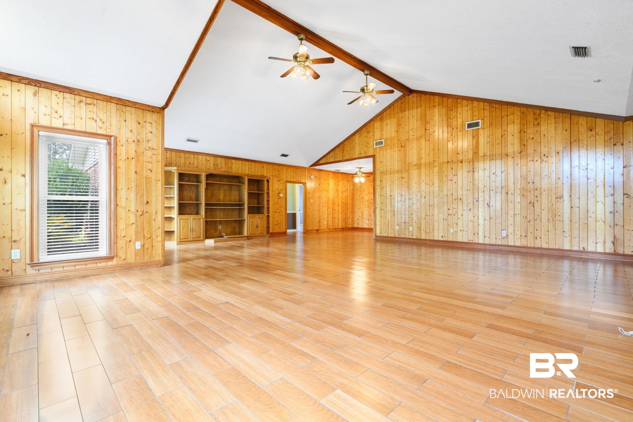 7540 2 Mile Road Irvington, AL 36544 - Photo 4 of 82 Expansive room featuring wood-finish flooring, wood-paneled walls, and a vaulted ceiling with exposed wood beams
