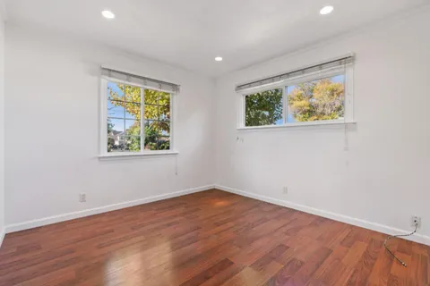 an empty room with wooden floor and window