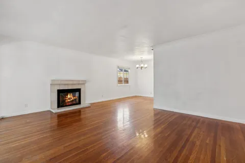 a view of an empty room with wooden floor and a fireplace