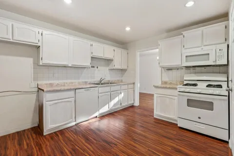 a kitchen with granite countertop white cabinets and white appliances