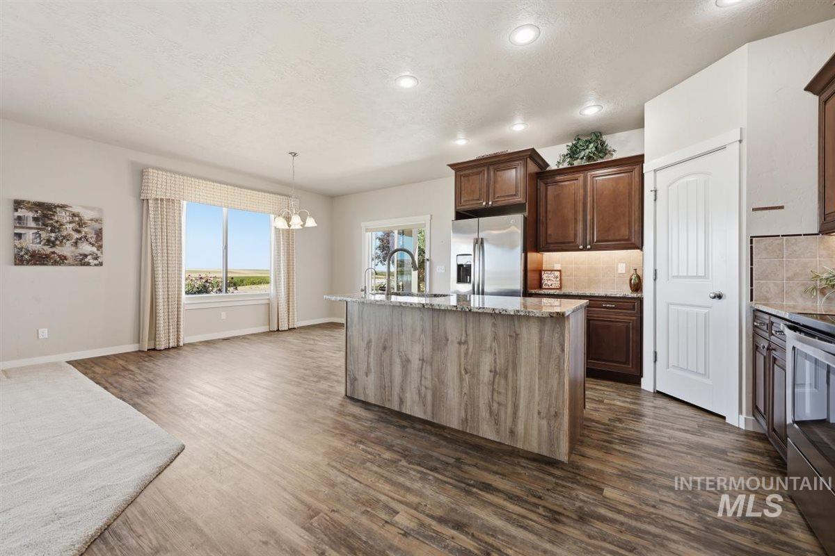 13496 Hockberger Ranch Road Caldwell, ID 83607 - Photo 13 of 40 Open-concept living space featuring wood-finish flooring, recessed lighting, and a kitchen island with stone countertops