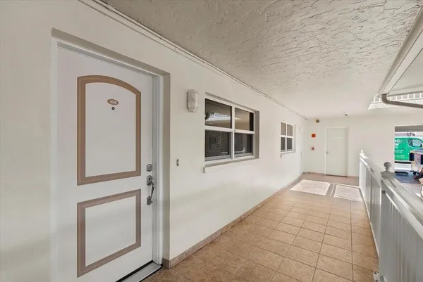 a view of a hallway to a bedroom with wooden floor and windows