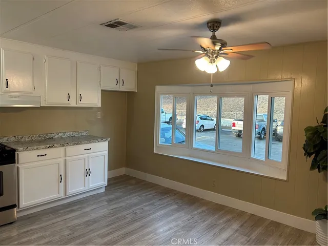 a kitchen with granite countertop a stove a sink and a refrigerator with wooden floors