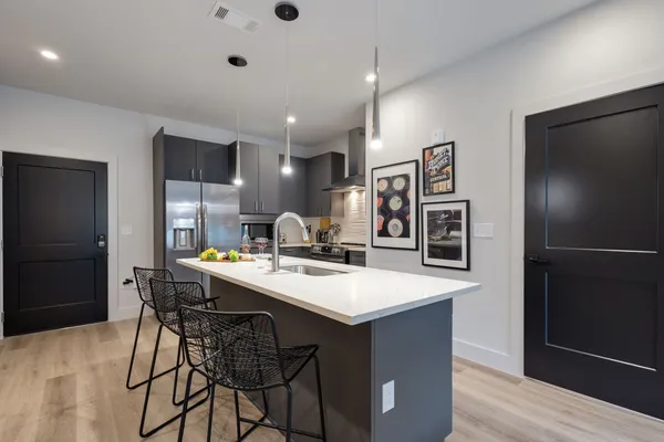 a kitchen with stainless steel appliances kitchen island a table chairs and a refrigerator