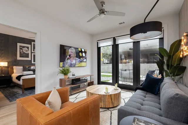 a living room with furniture a flat screen tv and a large window