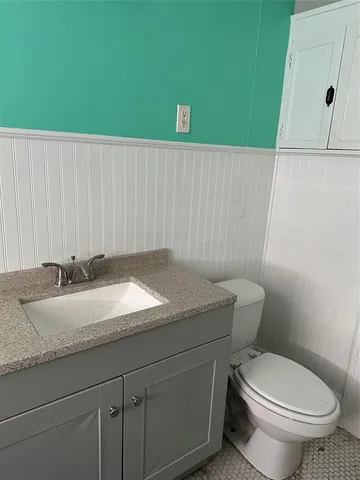 a bathroom with a granite countertop sink and a toilet