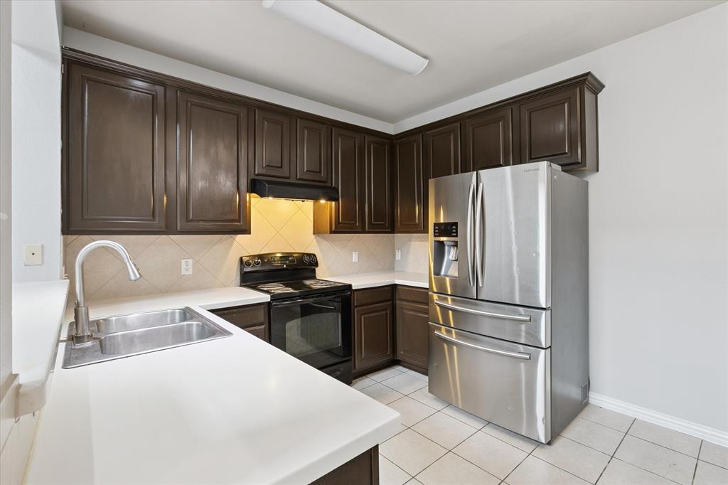 2202 Sandshell Street Bedford, TX 76021 - Photo 17 of 40 Kitchen featuring dark brown cabinetry, stainless steel fridge with ice dispenser, light countertops, black / electric stove, and light tile patterned floors