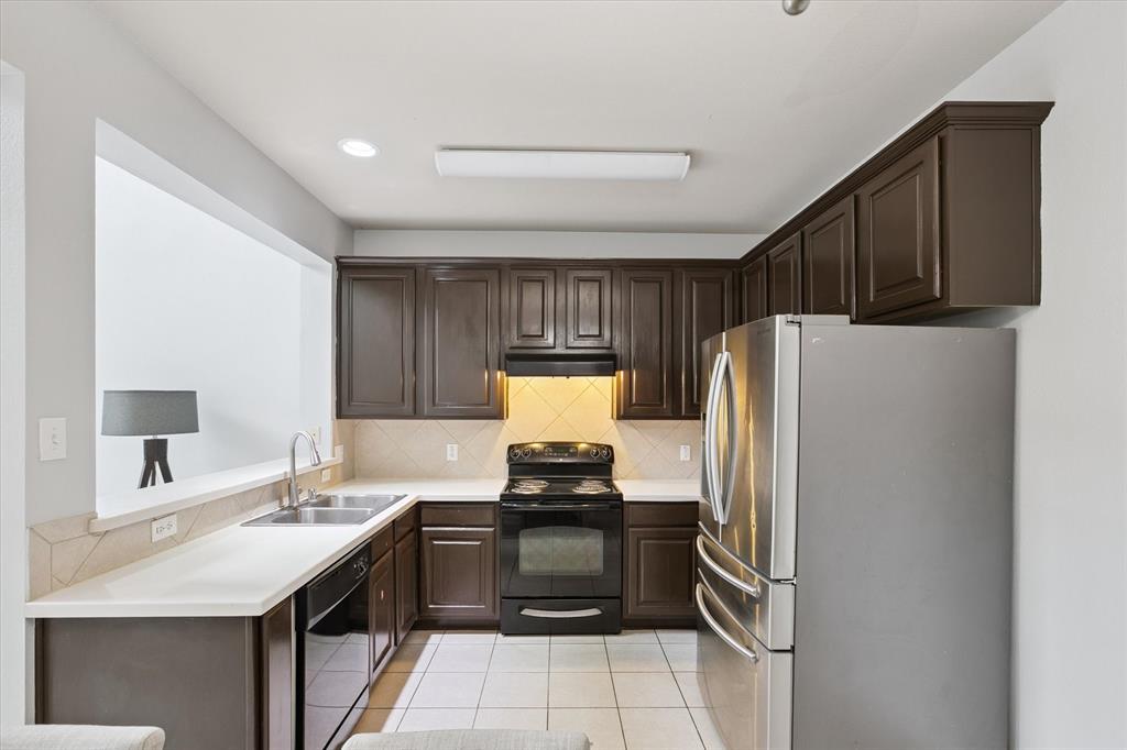 2202 Sandshell Street Bedford, TX 76021 - Photo 18 of 40 Kitchen featuring dark brown cabinets, tasteful backsplash, black appliances, light tile patterned floors, and light countertops