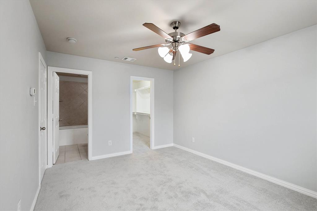 2202 Sandshell Street Bedford, TX 76021 - Photo 23 of 40 Unfurnished bedroom with light carpet, a ceiling fan, a walk in closet, and ensuite bathroom