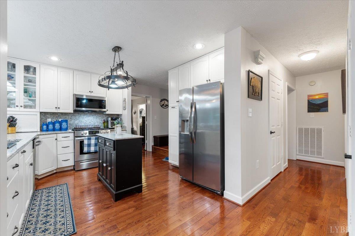 1765 Heron Pointe Drive Gretna, VA 24557 - Photo 13 of 64 a kitchen with stainless steel appliances granite countertop a refrigerator a stove top oven a sink dishwasher and a refrigerator with wooden floor