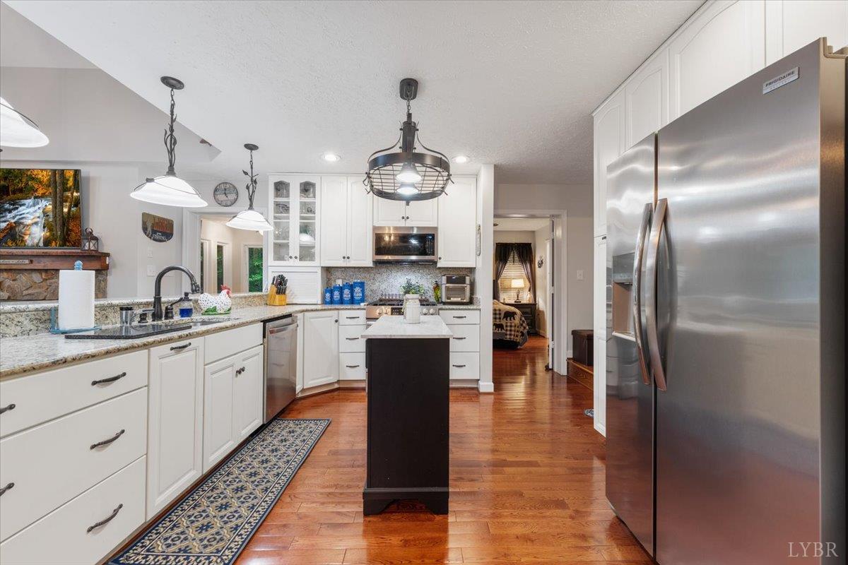 1765 Heron Pointe Drive Gretna, VA 24557 - Photo 15 of 64 a kitchen with stainless steel appliances kitchen island granite countertop a refrigerator a sink dishwasher a stove and white cabinets with wooden floor