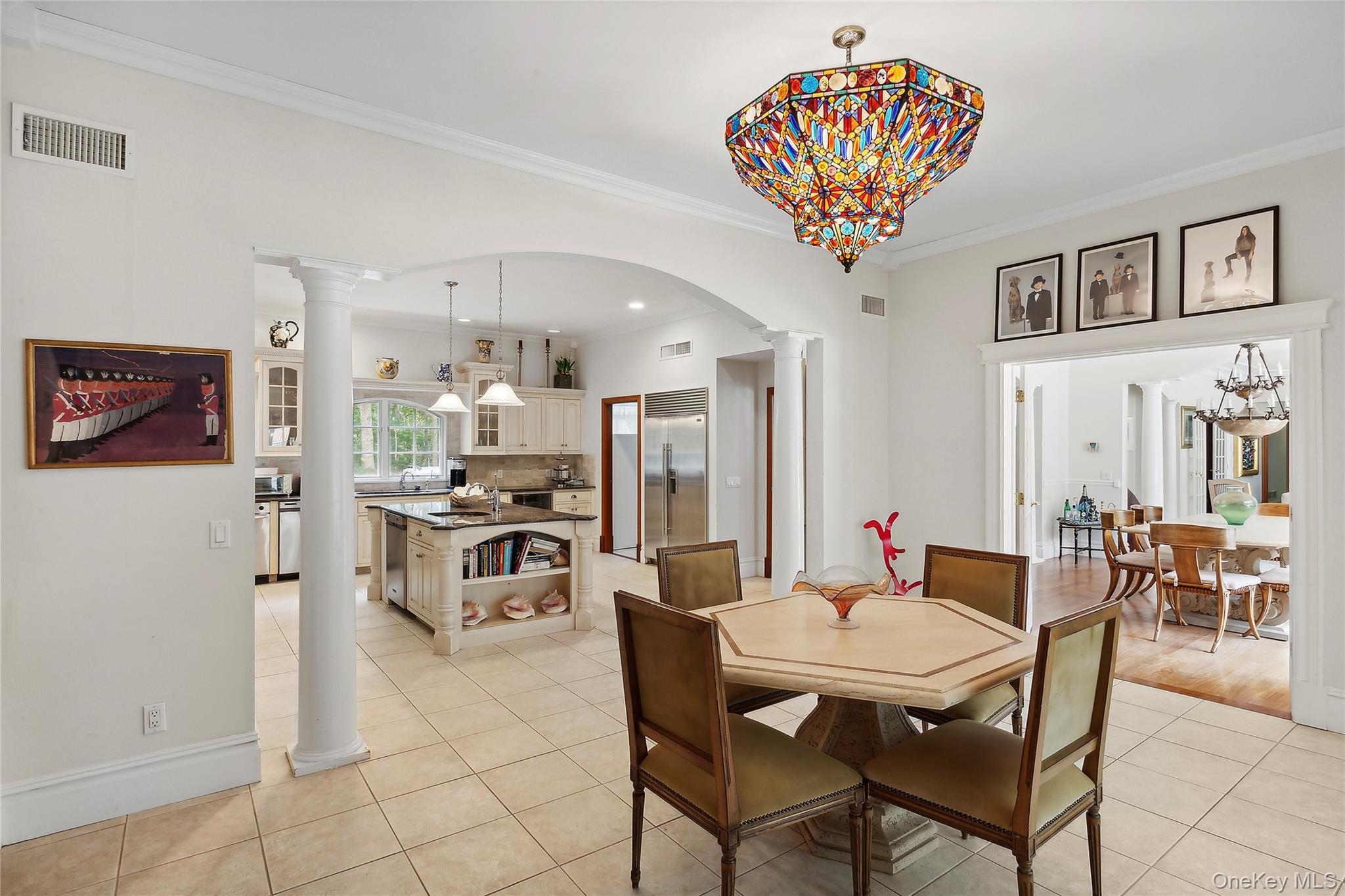 1 Terrys Trail East Hampton, NY 11937 - Photo 21 of 25 Dining space featuring decorative columns, light tile patterned floors, arched walkways, ornamental molding, and a chandelier