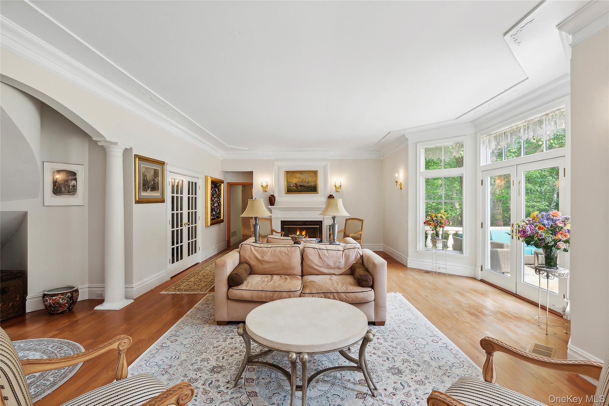 1 Terrys Trail East Hampton, NY 11937 - Photo 6 of 25 Living room with a warm lit fireplace, wood finished floors, french doors, arched walkways, and ornamental molding