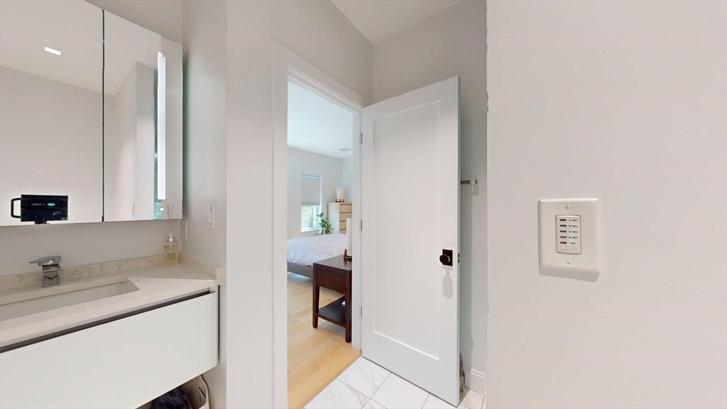 21 Crowninshield Road, Unit 17 Brookline, MA 02446 - Photo 14 of 29 a en suite bathroom with a granite countertop sink and a mirror
