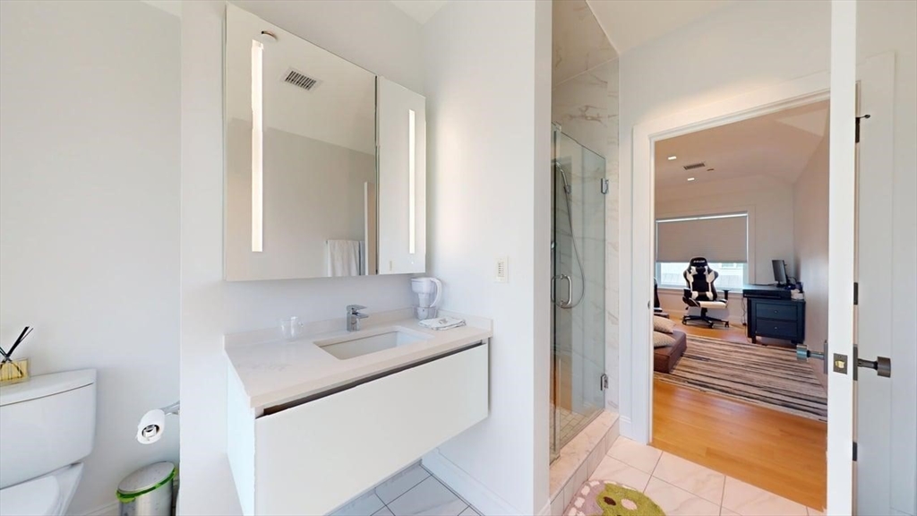 21 Crowninshield Road, Unit 17 Brookline, MA 02446 - Photo 20 of 29 a en suite bathroom with a granite countertop sink and a mirror