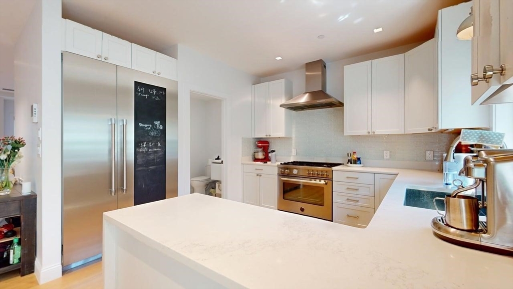 21 Crowninshield Road, Unit 17 Brookline, MA 02446 - Photo 6 of 29 a kitchen with stainless steel appliances kitchen island wooden cabinets a stove and a refrigerator