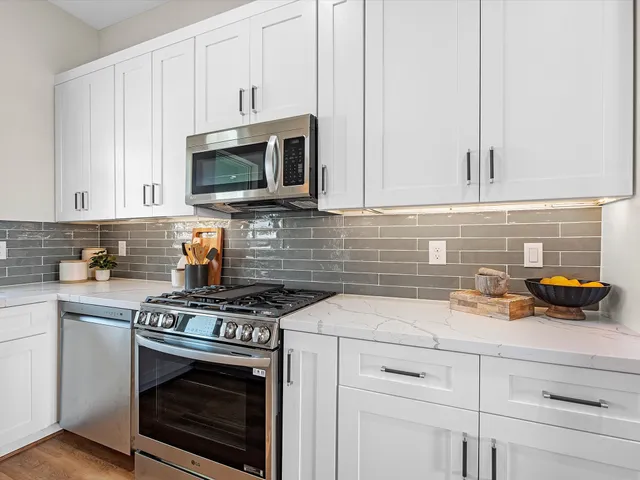 a kitchen with granite countertop white cabinets and stainless steel appliances