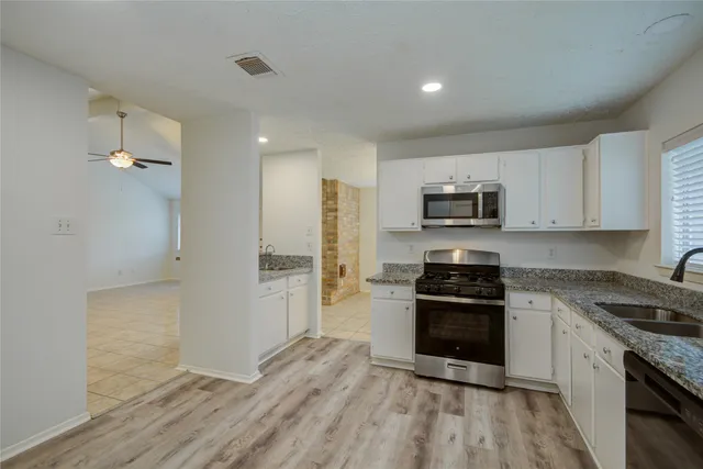a kitchen with granite countertop a refrigerator and a stove top oven