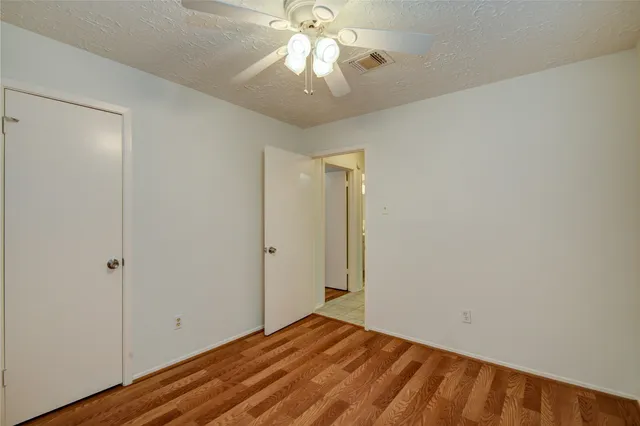 a view of an empty room and chandelier fan