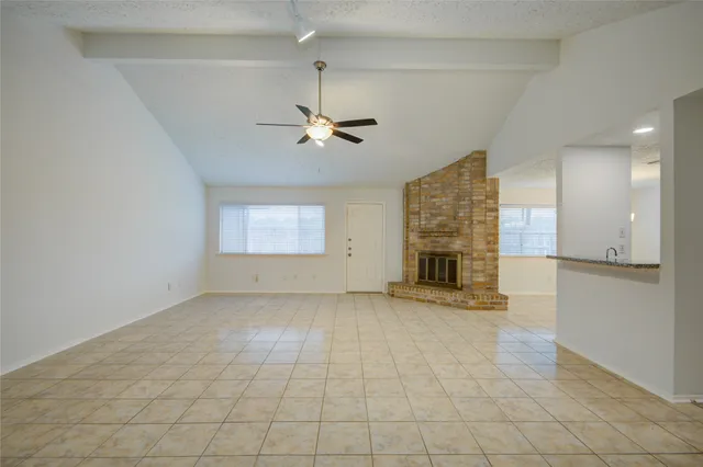 an empty room with windows and fireplace