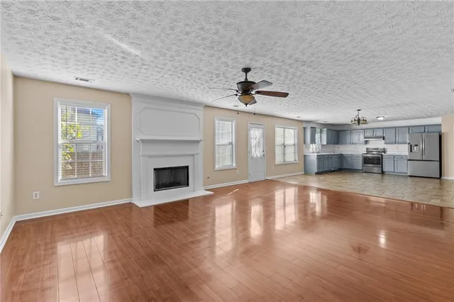 a view of a livingroom with a fireplace a ceiling fan and windows