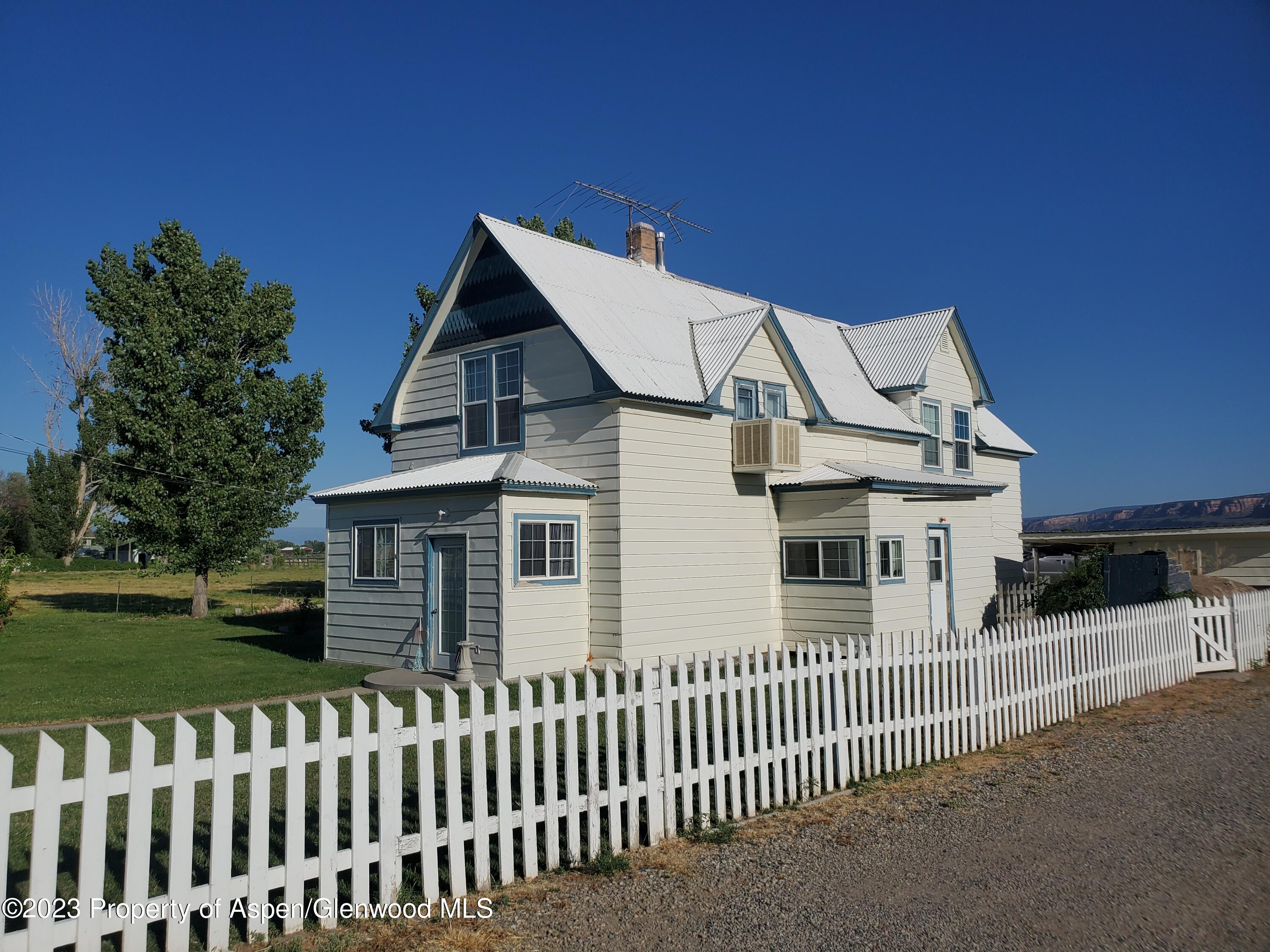 1877 J 6/10 Road Fruita, CO 81521 - Photo 8 of 38 a view of a white house with a small yard and wooden fence