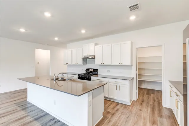 a kitchen that has a sink a stove and wooden floor