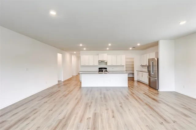 a view of kitchen with kitchen island sink refrigerator and white cabinets