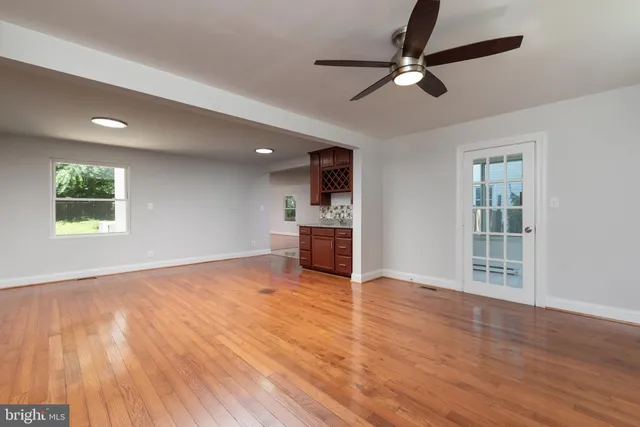 a view of an empty room with window and wooden floor