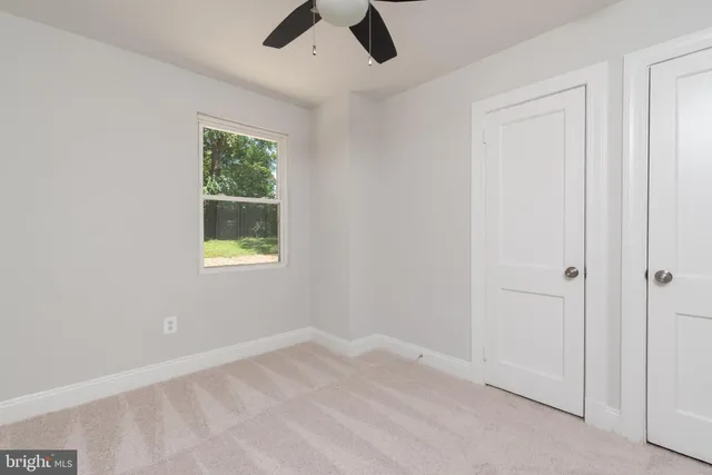 an empty room with a window and a ceiling fan
