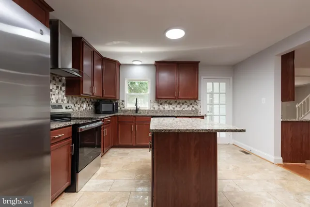 a kitchen with stainless steel appliances granite countertop a stove a sink and a microwave