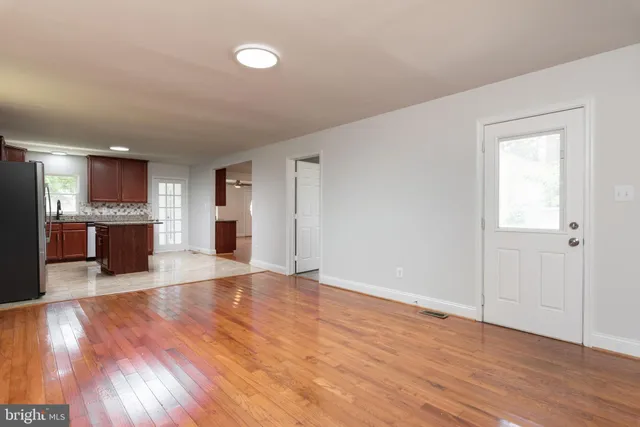 a view of a electric appliances in kitchen and empty room with wooden floor