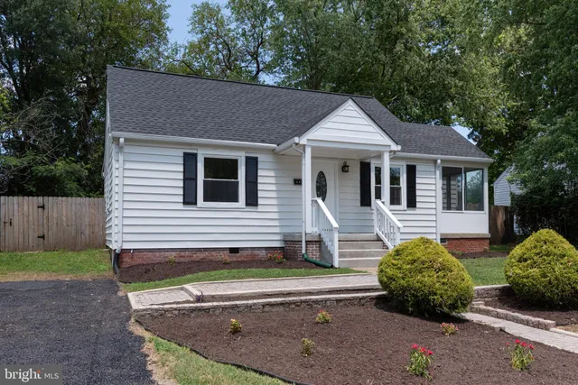 a view of a house with a yard plants and large tree