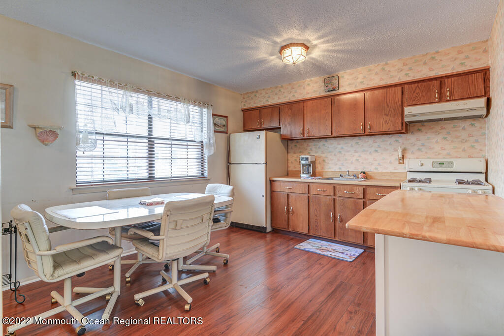 494 Rena Court Brick, NJ 08724 - Photo 6 of 18 a kitchen with a table chairs refrigerator a sink dishwasher and cabinets with wooden floor