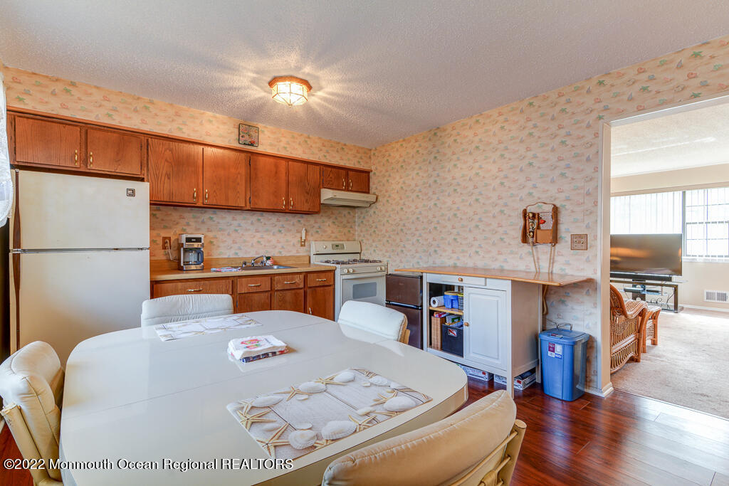 494 Rena Court Brick, NJ 08724 - Photo 7 of 18 a kitchen with stainless steel appliances granite countertop a refrigerator a sink dishwasher a stove and a dining table with wooden floor