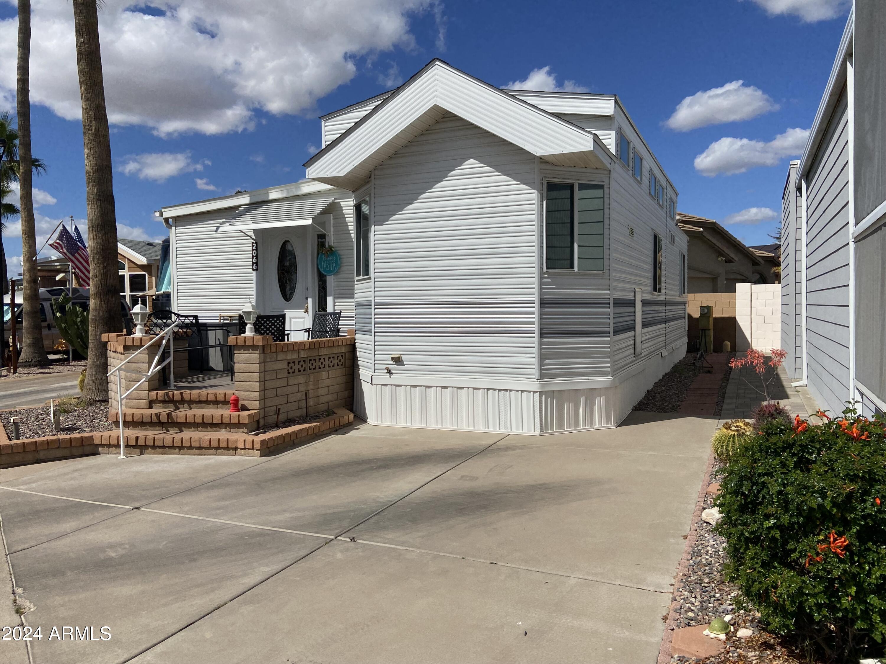 2066 West Klamath Avenue, Unit 66 Apache Junction, AZ 85119 - Photo 32 of 35 a view of a house with a small yard and potted plants