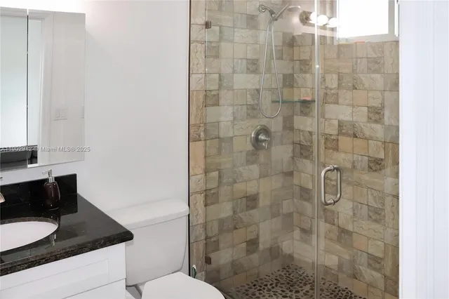 a bathroom with a granite countertop shower a toilet and sink