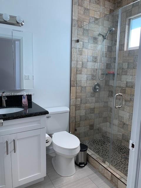 94825 Overseas Highway, Unit 172 Key Largo, FL 33037 - Photo 18 of 40 a bathroom with a granite countertop toilet a sink a mirror and shower