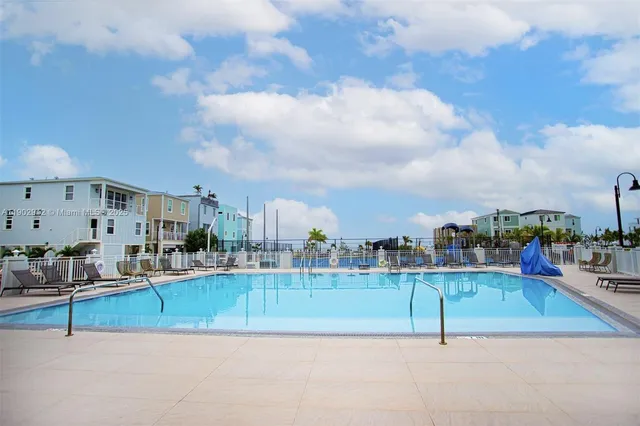 a view of swimming pool that has lawn chairs with large trees
