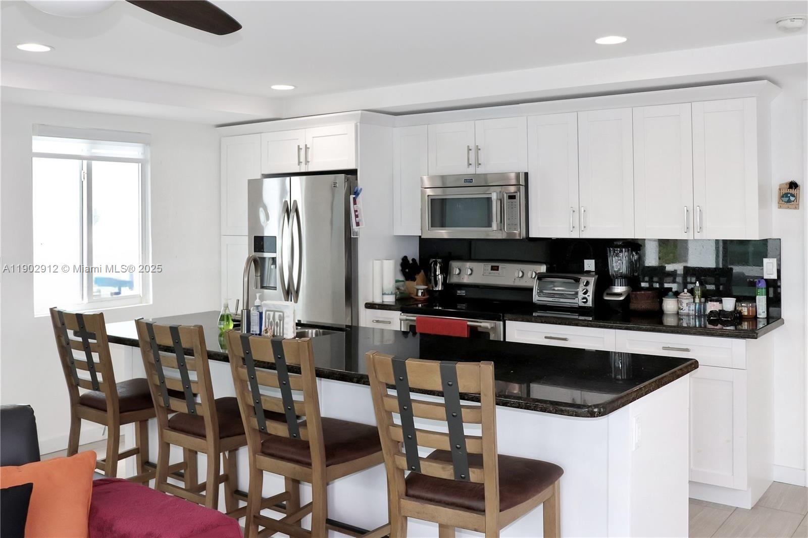 94825 Overseas Highway, Unit 172 Key Largo, FL 33037 - Photo 9 of 40 a kitchen with stainless steel appliances granite countertop a table chairs microwave and sink