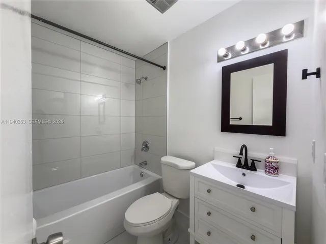 a bathroom with a toilet a sink a mirror a bathtub and vanity