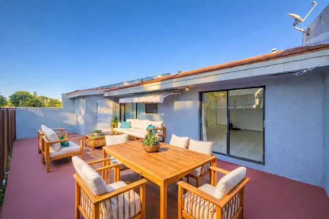 a patio with table and chairs and potted plants