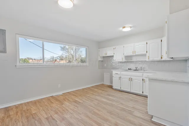 a kitchen with granite countertop white cabinets and wooden floor