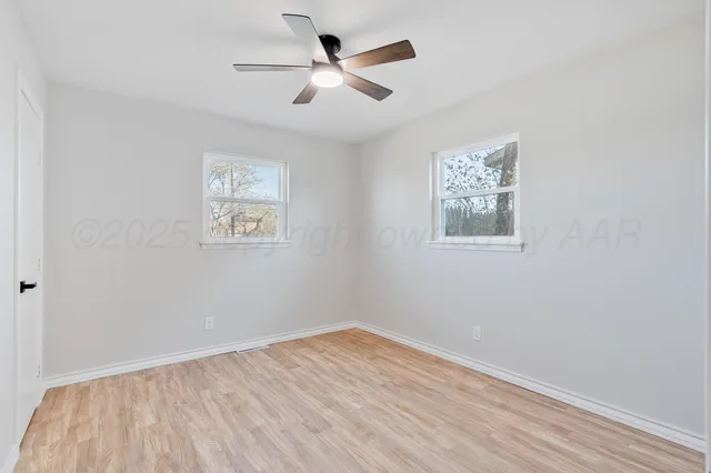 an empty room with wooden floor and ceiling fan