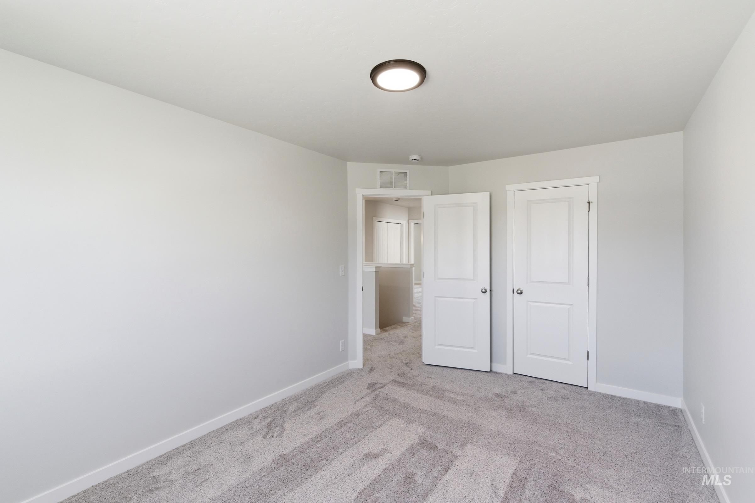 13677 Redway Court Caldwell, ID 83607 - Photo 20 of 35 Carpeted interior room featuring light gray wall paint, white baseboards, and a flush-mount ceiling light fixture