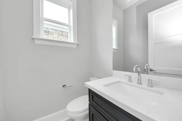 a bathroom with a granite countertop toilet sink and mirror