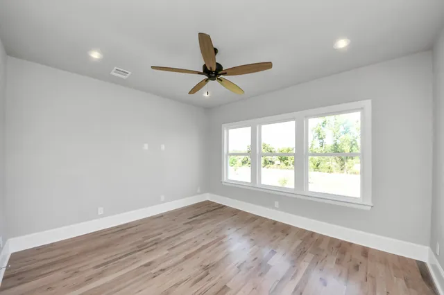 an empty room with wooden floor and a ceiling fan