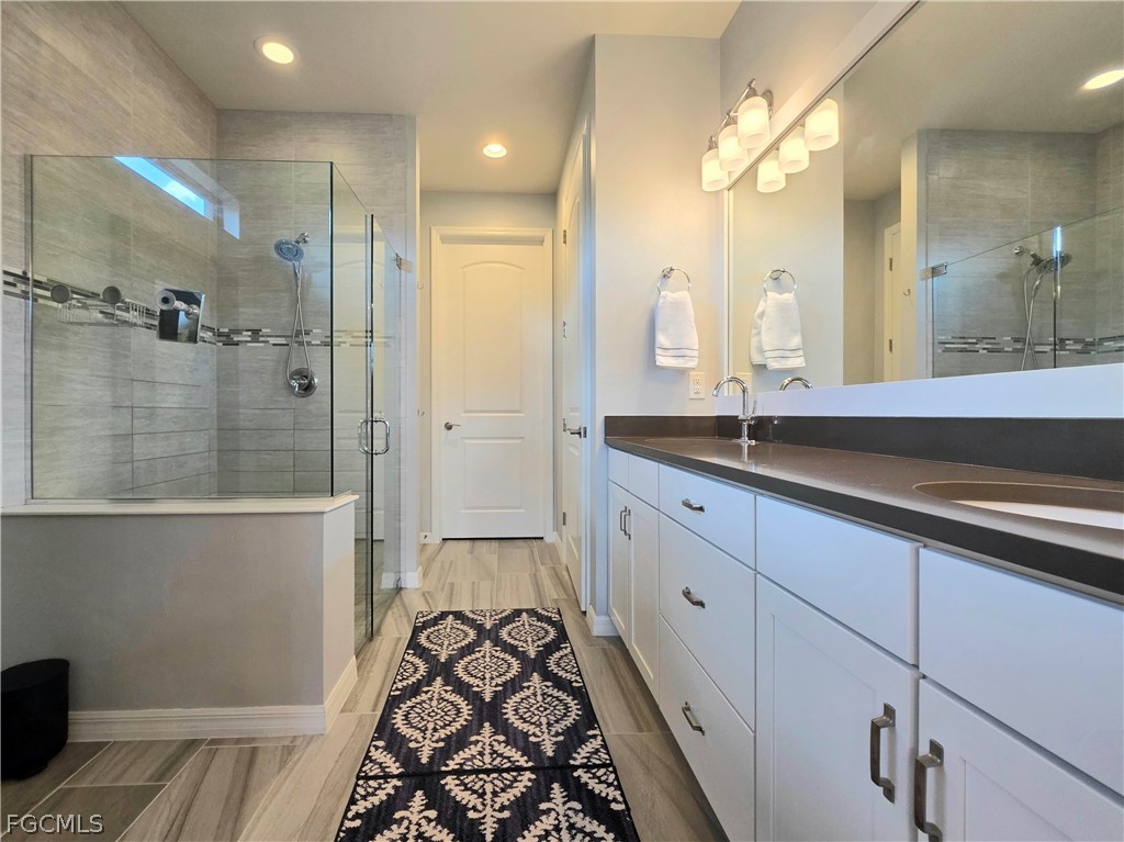 10805 Dennington Road Fort Myers, FL 33913 - Photo 16 of 45 a spacious bathroom with a double vanity sink a large mirror a shower and a bathtub