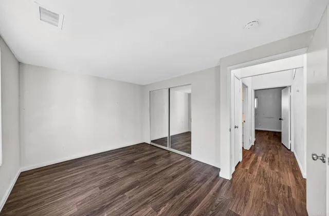 a view of a hallway with wooden floor and a bathroom