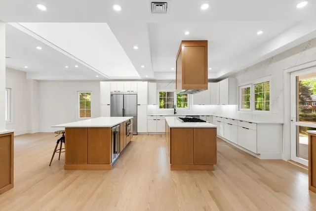 a large kitchen with stainless steel appliances a large counter top a stove a chimney a sink and a large window